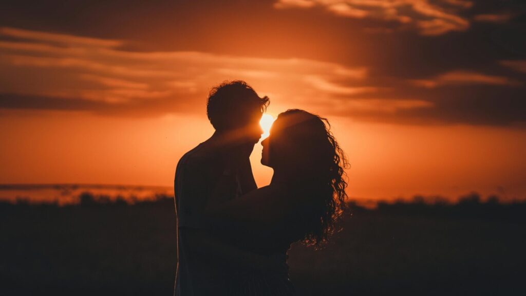 Pareja besandose durante la puesta de sol