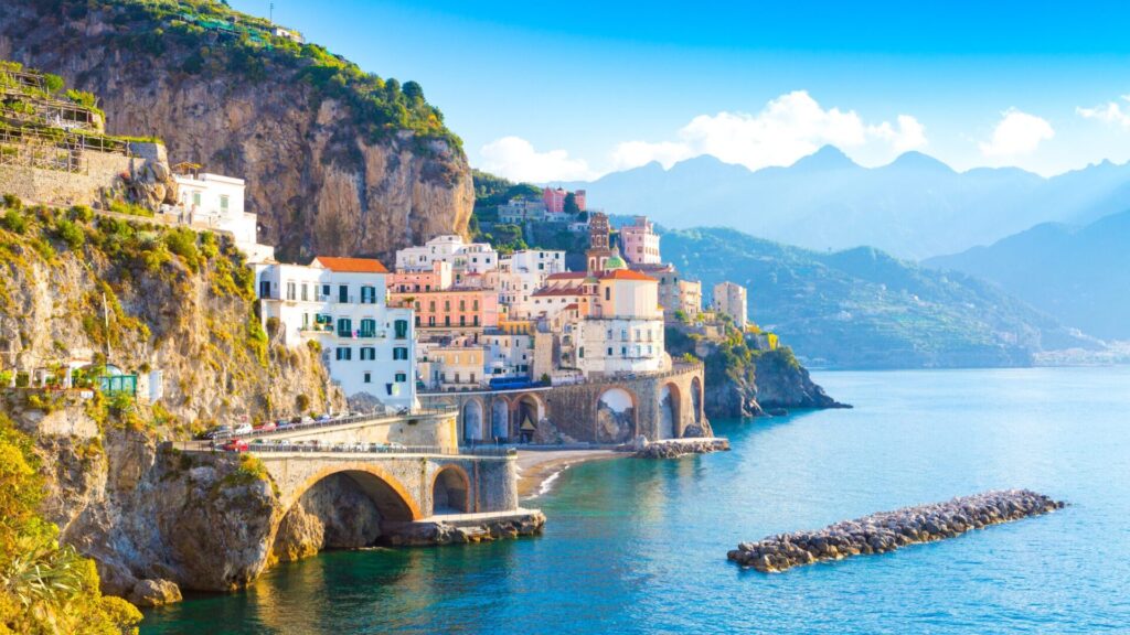 Panorámica de la Costa Amalfitana con acantilados escarpados, casas color pastel y el mar Tirreno de fondo.