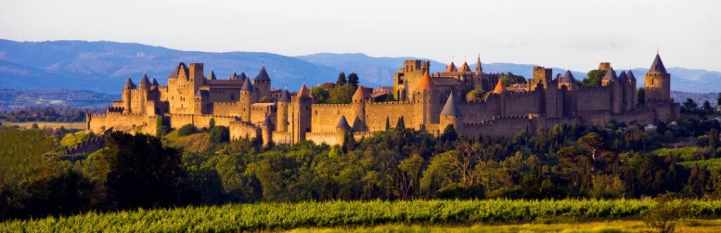 Castillo histórico en el campo francés, rodeado de jardines verdes y arquitectura medieval.
