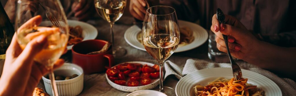 People sharing a spaghetti dinner with wine
