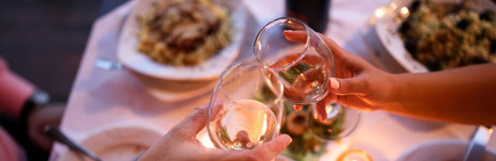 Two people toasting with a glass of wine at a romantic dinner
