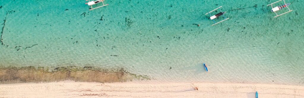 Bird's-eye view of a paradise beach with crystal clear water and boats

