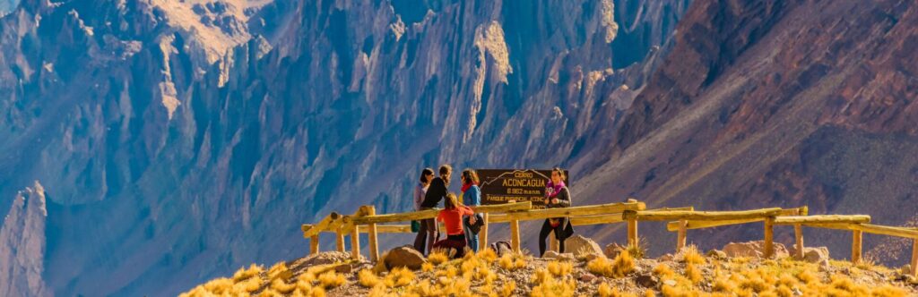 Familia en el pico de una montaña rodeada de más montañas rocosas