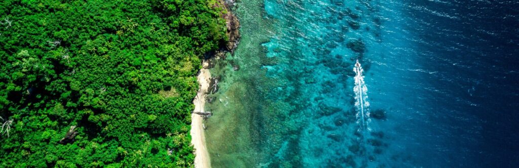Vista aérea de un paisaje paradisíaco que combina verde de la naturaleza y azul cristalino del mal