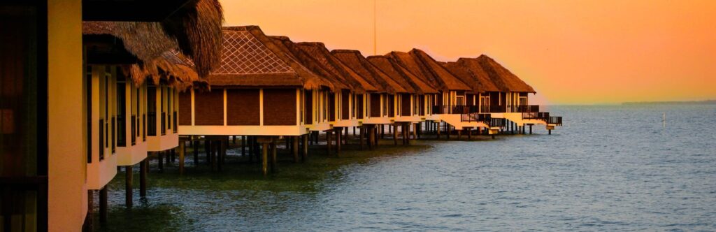 Imagen de unas cabañas encima del mar al atardecer
