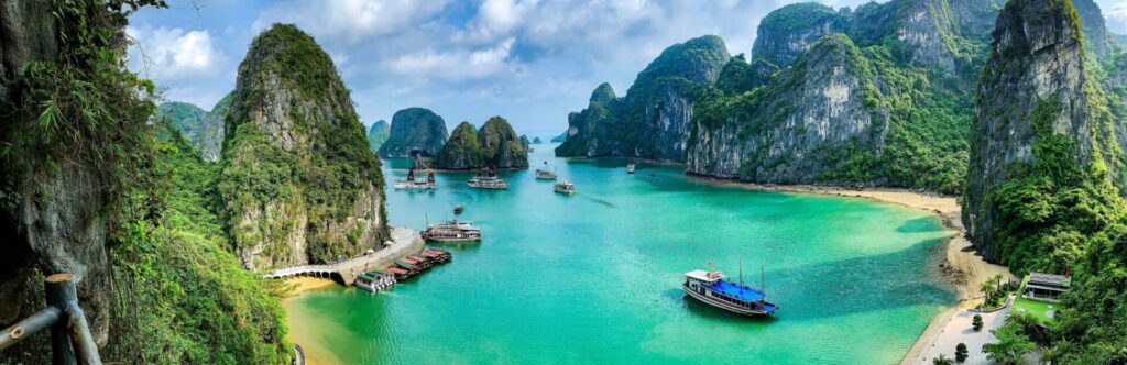 Views of an island with crystal clear water surrounded by rocks and boats sailing by